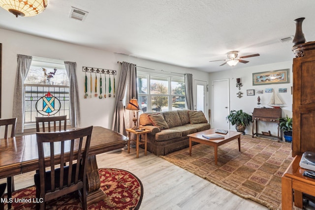 living room featuring hardwood / wood-style flooring, ceiling fan, and a textured ceiling