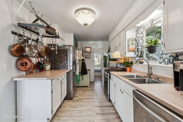 kitchen featuring white cabinets, sink, appliances with stainless steel finishes, and light hardwood / wood-style flooring