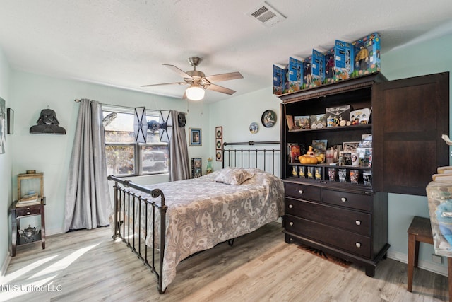 bedroom with a textured ceiling, light hardwood / wood-style floors, and ceiling fan