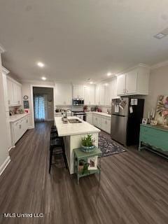 kitchen featuring dark hardwood / wood-style flooring, white cabinetry, a kitchen bar, sink, and stainless steel appliances