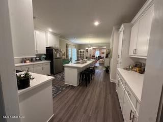 kitchen featuring white cabinetry, dark wood-type flooring, a breakfast bar, and a kitchen island with sink