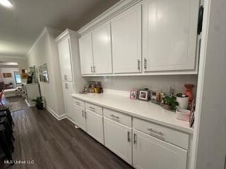 bar with ornamental molding, white cabinets, and dark hardwood / wood-style flooring