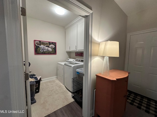 laundry room with cabinets, washer and dryer, and wood-type flooring