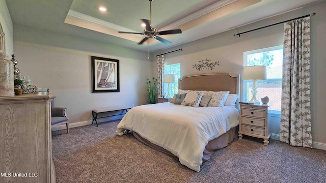 carpeted bedroom featuring a raised ceiling, multiple windows, and ceiling fan