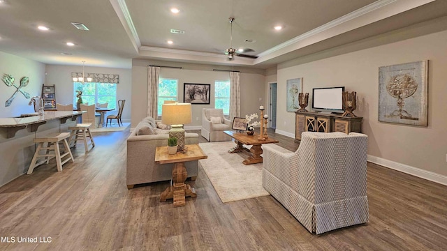 living room featuring sink, dark hardwood / wood-style flooring, a tray ceiling, ceiling fan with notable chandelier, and ornamental molding