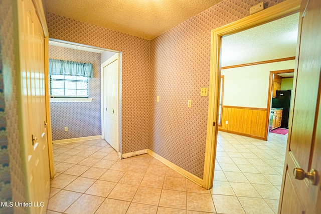 corridor with a textured ceiling and light tile patterned floors