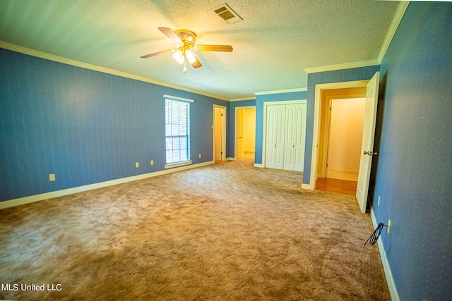 unfurnished bedroom with ornamental molding, a textured ceiling, carpet, and ceiling fan