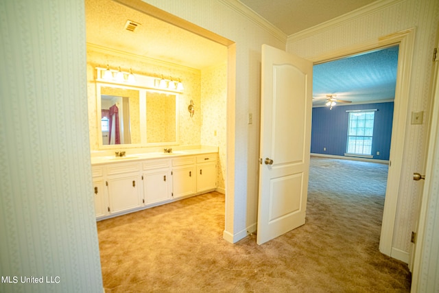 hallway featuring a textured ceiling, ornamental molding, sink, and light colored carpet