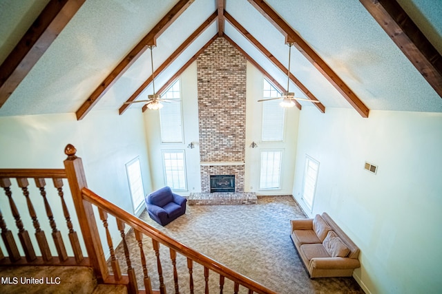 carpeted living room featuring beamed ceiling, a healthy amount of sunlight, high vaulted ceiling, and a brick fireplace