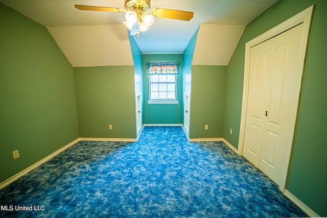 additional living space with ceiling fan, a textured ceiling, and dark carpet