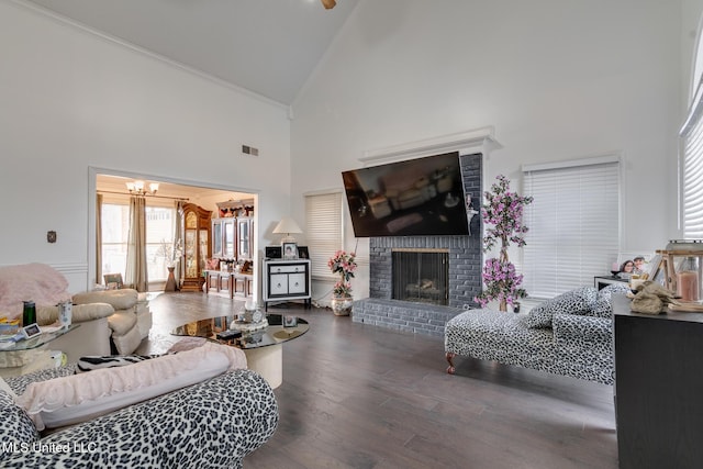 living room featuring an inviting chandelier, hardwood / wood-style flooring, a fireplace, and high vaulted ceiling