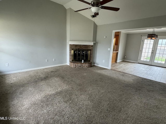 unfurnished living room with lofted ceiling, light carpet, french doors, ceiling fan, and a fireplace