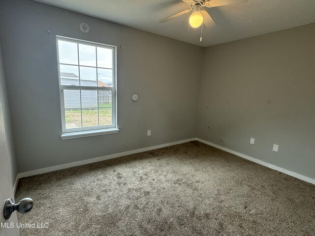 spare room with carpet, a wealth of natural light, and ceiling fan