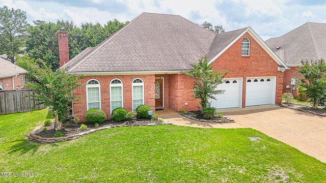 view of front of property with driveway, a chimney, a front yard, brick siding, and fence
