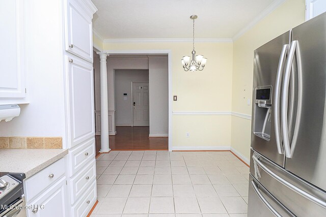 kitchen featuring crown molding, white cabinets, stainless steel fridge, stove, and decorative columns