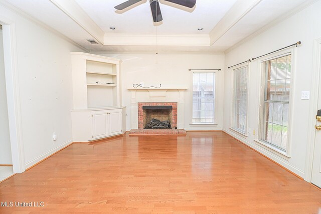 unfurnished living room featuring light wood-style floors, a raised ceiling, ornamental molding, and a fireplace