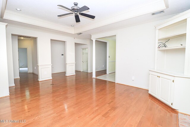 unfurnished living room with ceiling fan, visible vents, crown molding, light wood-style floors, and ornate columns