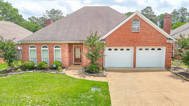 traditional home featuring a chimney, an attached garage, driveway, and brick siding