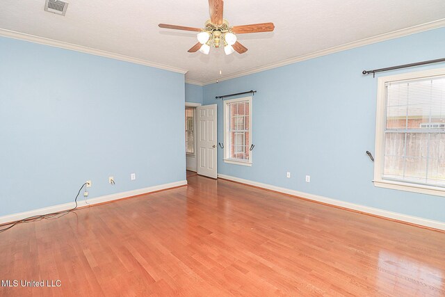empty room with baseboards, ceiling fan, wood finished floors, and visible vents