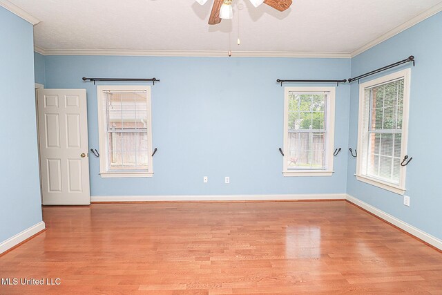 spare room featuring crown molding, baseboards, ceiling fan, and wood finished floors