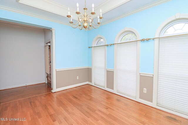 unfurnished dining area with baseboards, ornamental molding, wood finished floors, and a chandelier