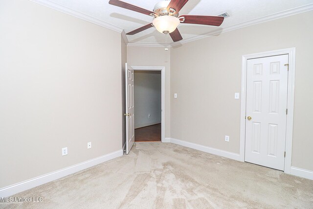 carpeted empty room with crown molding, baseboards, a ceiling fan, and visible vents