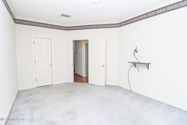 unfurnished bedroom with crown molding, carpet flooring, visible vents, and baseboards