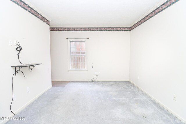 spare room with baseboards, ornamental molding, and carpet