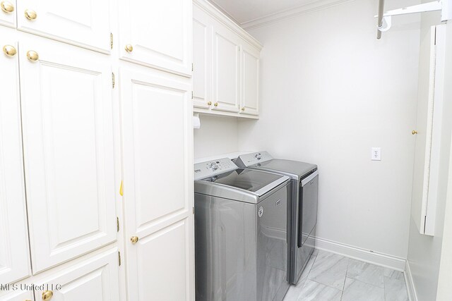 clothes washing area featuring ornamental molding, marble finish floor, washing machine and dryer, baseboards, and cabinet space