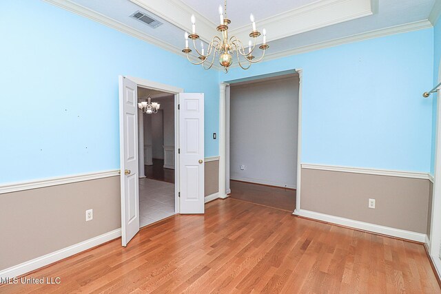 unfurnished dining area featuring visible vents, baseboards, light wood finished floors, an inviting chandelier, and ornamental molding