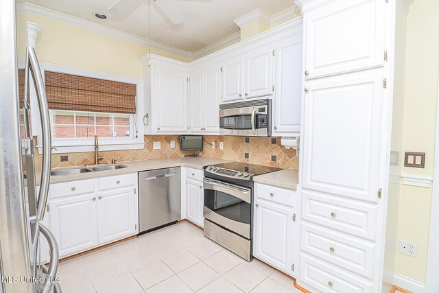 kitchen with crown molding, a sink, light countertops, stainless steel appliances, and decorative backsplash
