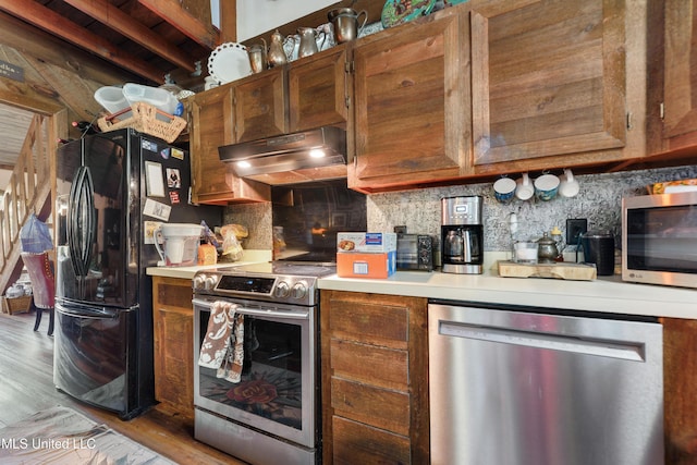 kitchen with decorative backsplash, stainless steel appliances, and light hardwood / wood-style floors