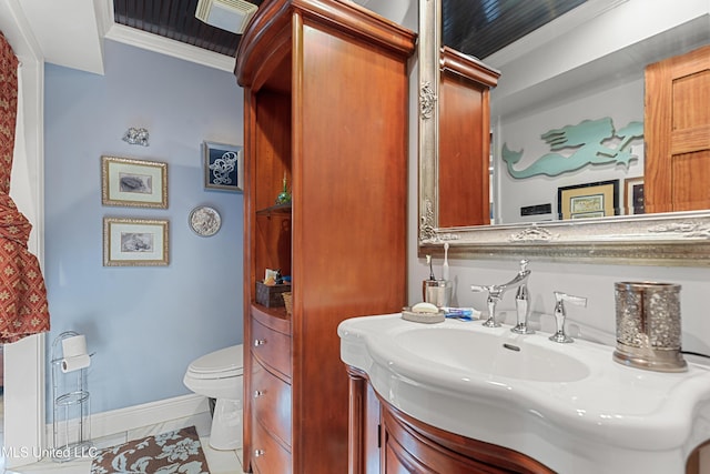 bathroom with toilet, vanity, tile patterned floors, and crown molding