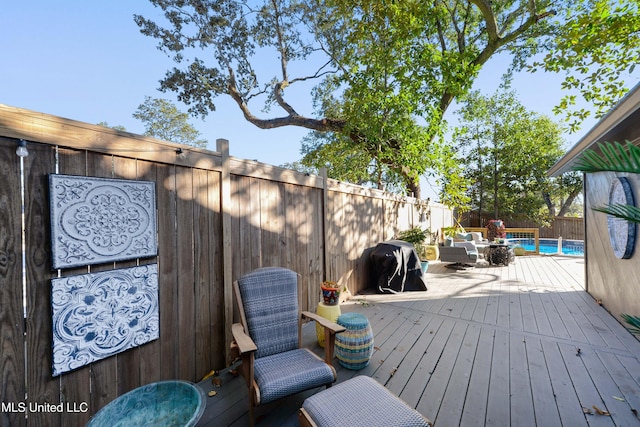 wooden terrace featuring outdoor lounge area, a fenced in pool, and grilling area