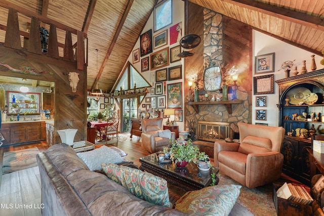 living room with wood-type flooring, high vaulted ceiling, a stone fireplace, and wooden walls