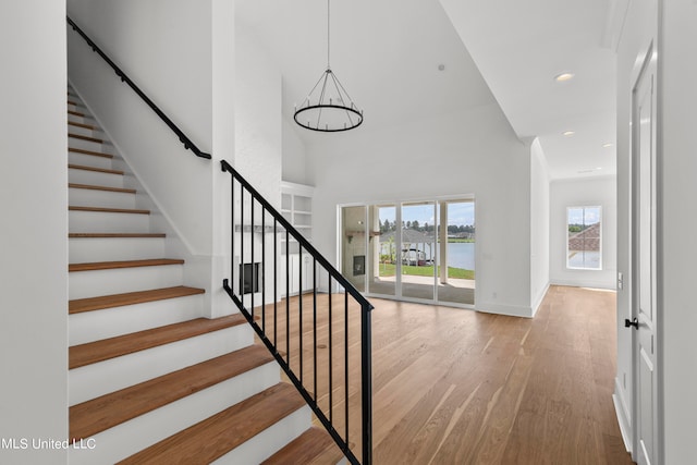 stairway with a high ceiling, hardwood / wood-style flooring, and a chandelier