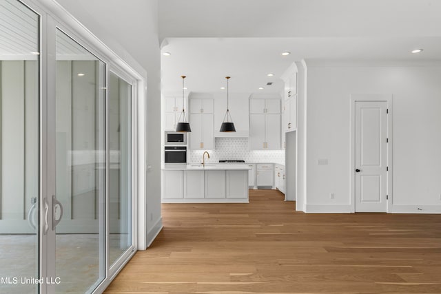 kitchen with white cabinets, tasteful backsplash, pendant lighting, light hardwood / wood-style floors, and sink