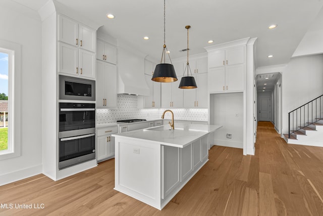 kitchen with sink, an island with sink, and white cabinets