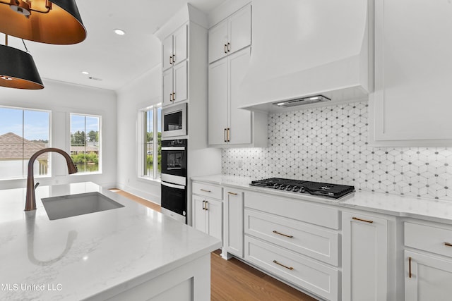 kitchen with appliances with stainless steel finishes, custom exhaust hood, white cabinetry, and sink