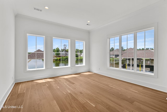 unfurnished room featuring crown molding, a water view, and light hardwood / wood-style floors