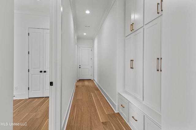 hallway with ornamental molding and light wood-type flooring