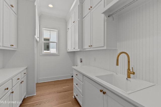 kitchen with light hardwood / wood-style flooring, white cabinetry, and sink