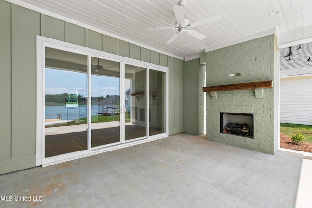 unfurnished living room featuring concrete floors, an outdoor stone fireplace, a water view, and ceiling fan