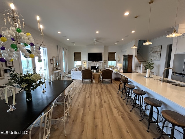 kitchen with ceiling fan, a breakfast bar, a fireplace, a sink, and light wood-style floors