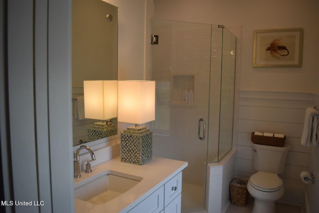 full bathroom with a stall shower, tile walls, vanity, and toilet