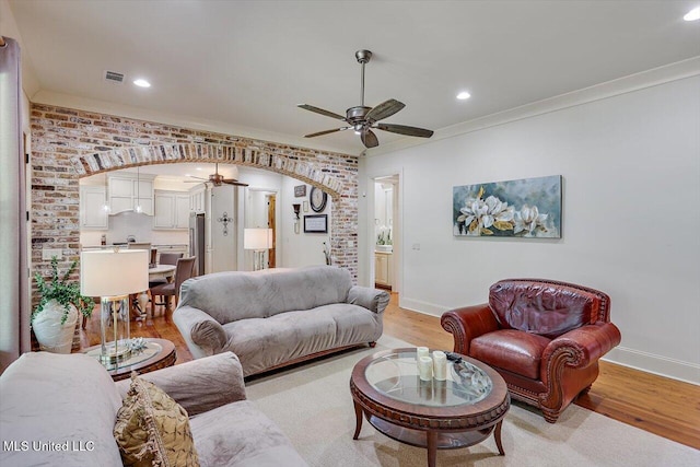 living room with light hardwood / wood-style floors, crown molding, and ceiling fan