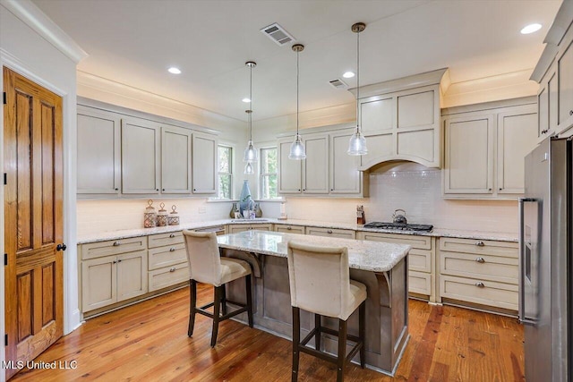 kitchen with light stone counters, a kitchen island, wood-type flooring, a kitchen bar, and stainless steel appliances