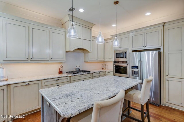 kitchen featuring stainless steel appliances, light hardwood / wood-style flooring, decorative light fixtures, and a kitchen island