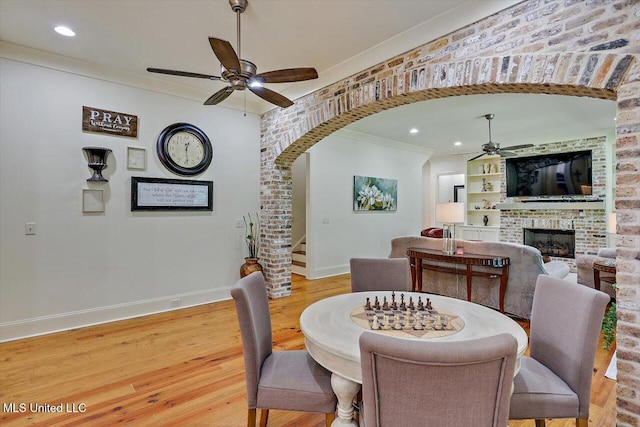 dining space featuring ceiling fan, ornamental molding, a fireplace, and hardwood / wood-style floors