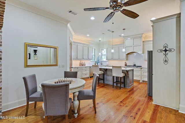 dining space with ornamental molding, light wood-type flooring, and ceiling fan